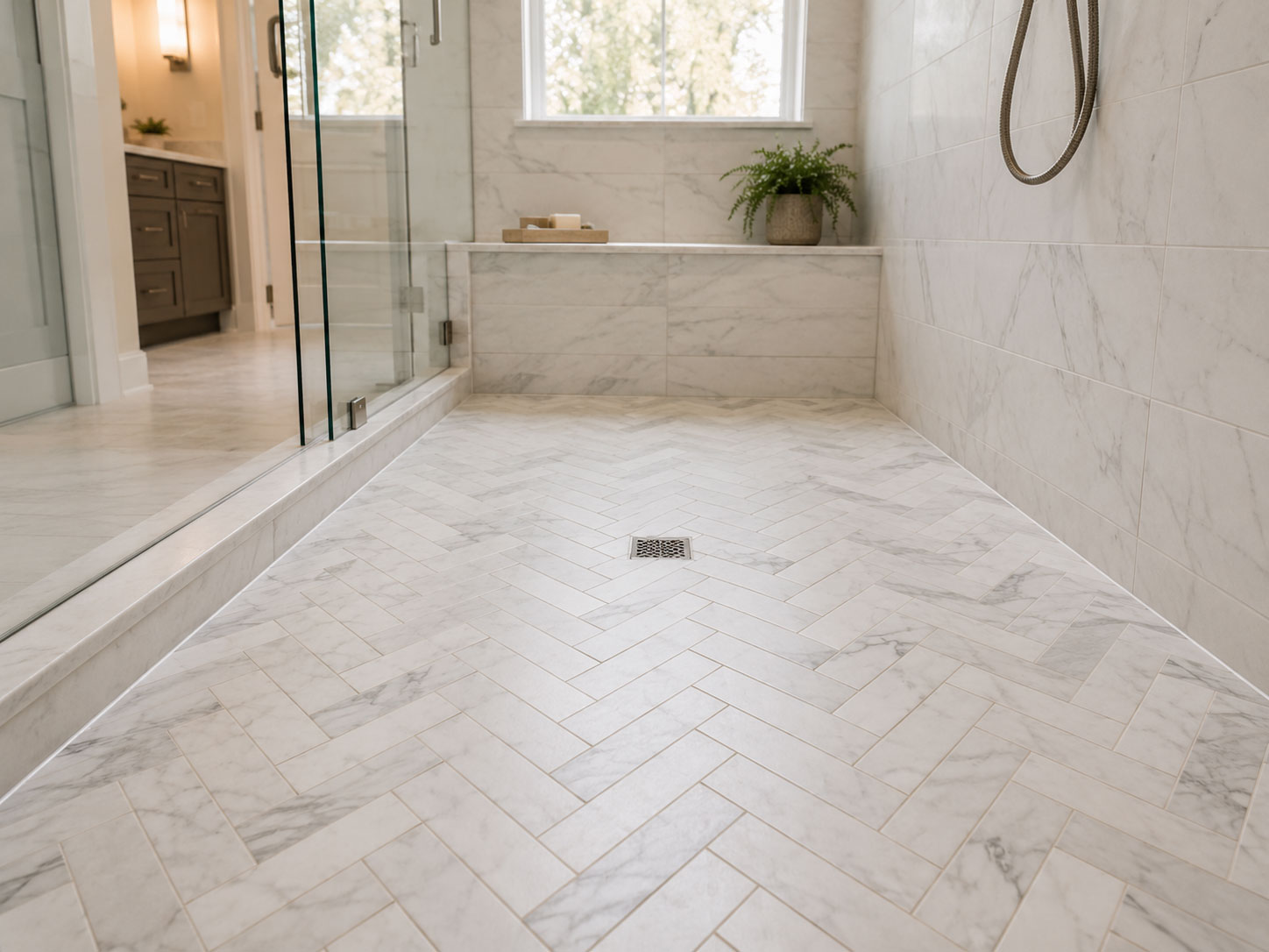 Walk-in shower with white herringbone tile floor, glass enclosure, and built-in bench.