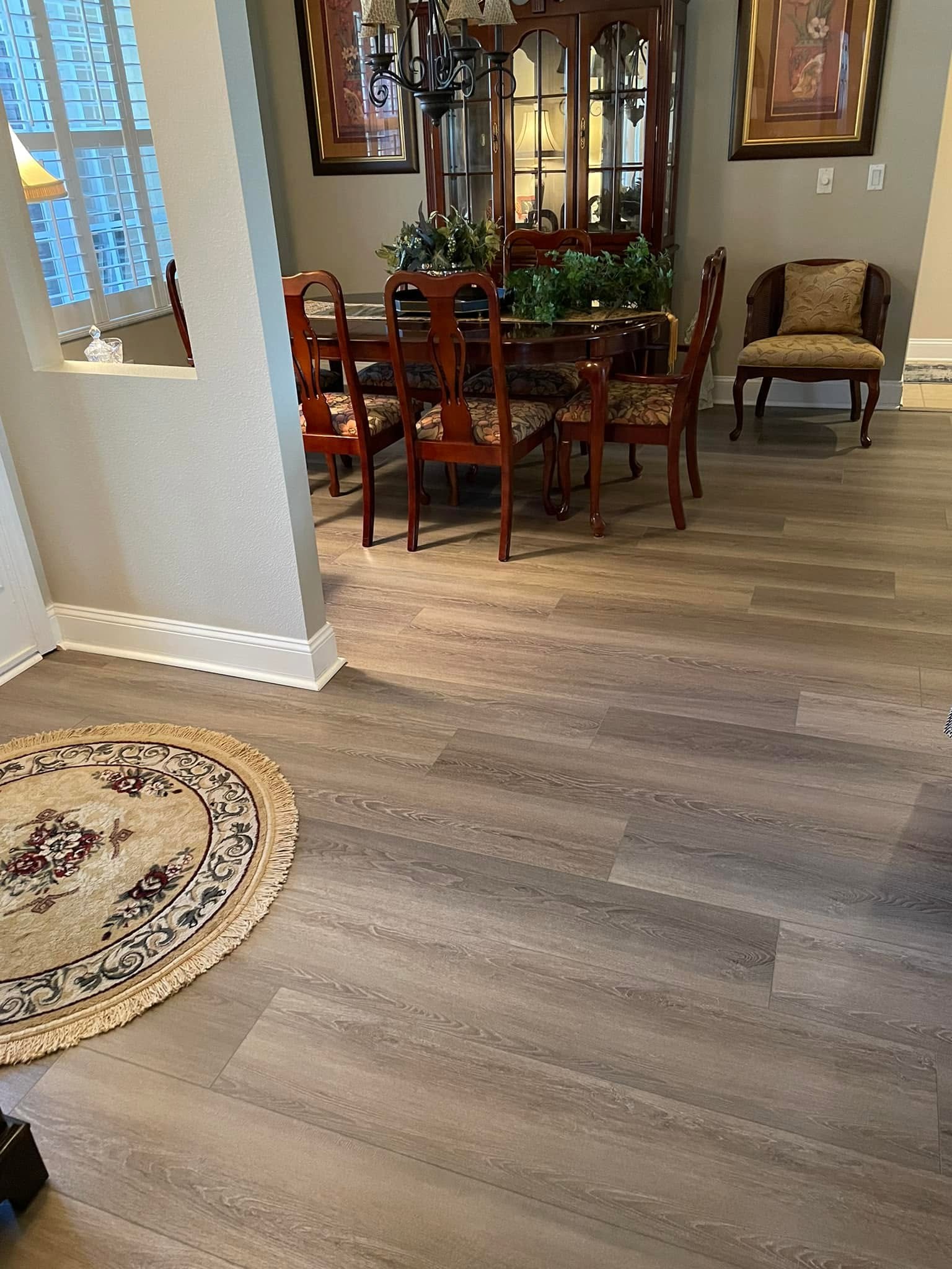 Gray wood-look vinyl plank flooring installed in an entryway and dining room.