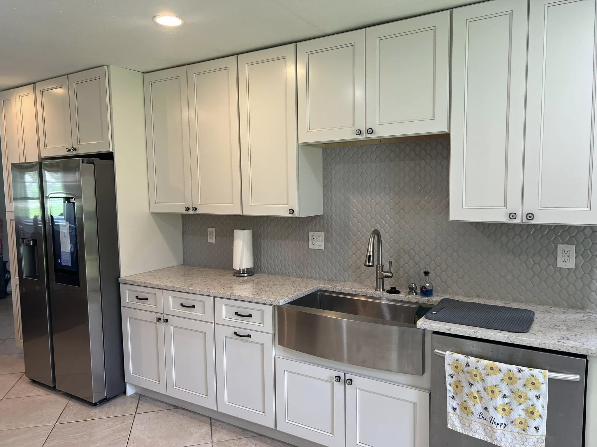 Modern kitchen with white shaker cabinets, quartz countertops, and a stainless steel farmhouse sink.