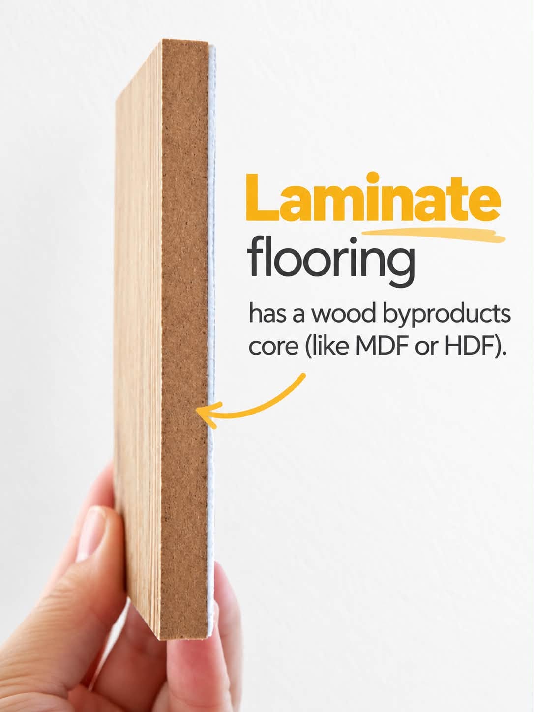 A hand holds a laminate flooring sample showing its wood fiber core.
